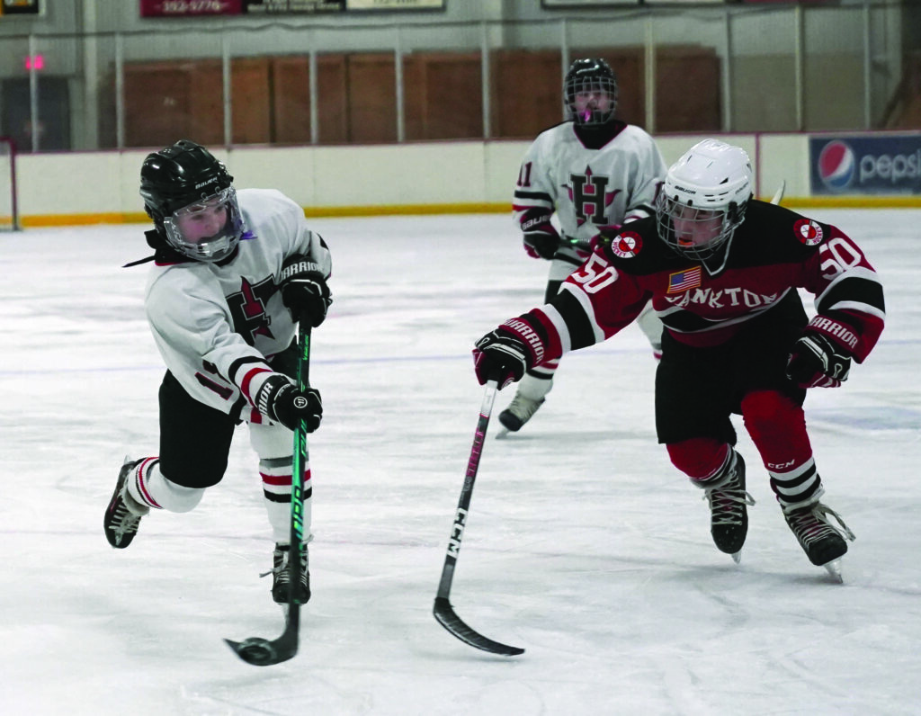 Mike Carroll/Plainsman
Huron’s Knox Jans shoots the puck against Logan Brunick of Yankton during the semifinals on Saturday. He scored on the play. 