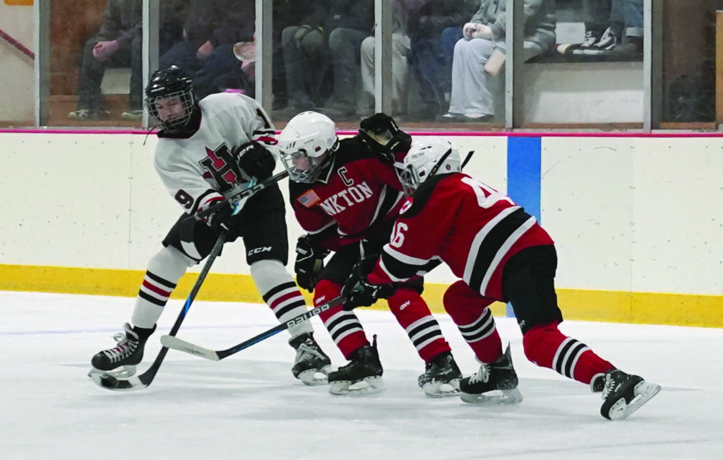Mike Carroll/Plainsman
Huron’s Benjamin Larson shoots the puck while being pressure by a pair of Yankton defenders during the semifinals on Saturday.  