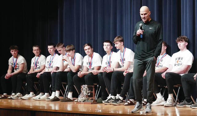 Coach Tim Buddenhagen addresses the crowd with the team seated behind him.
                                 Mike Carroll/Plainsman
