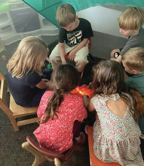 students pretend to roast marshmallows around a fake fire.
