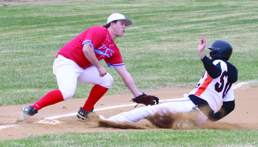 Benjamin Chase/Plainsman Chase Schuchhardt of the Tigers slides into third base around the tag of Lincoln’s Paxton Walters.