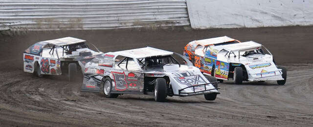 MIKE CARROLL/PLAINSMAN Scott Tyrrell of New Underwood leads Lorin Johnson of Miller, left, and Lane Johnson of Miller, right during their WISSOTA Midwest modified heat race on Saturday at DSFS.